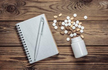 Defter ve ilaç şişesi ahşap bir masada. Üst görünüm