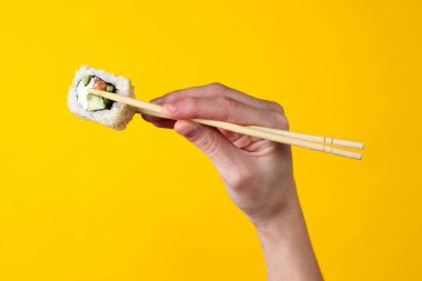 Sarı arka planda çubuklu suşi rulosu. Japon mutfağı