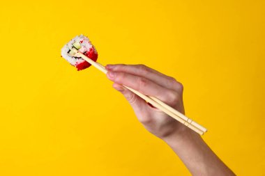 Sarı arka planda çubuklu suşi rulosu. Japon mutfağı