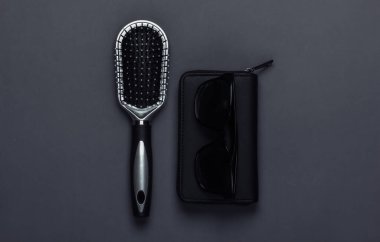 Siyah arka planda saç fırçası olan bir cüzdan. Kadın aksesuarları. Üst görünüm