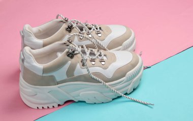 Pembe arka planda yüksek tabanlı (platform) şık spor ayakkabılar. Minimalizm