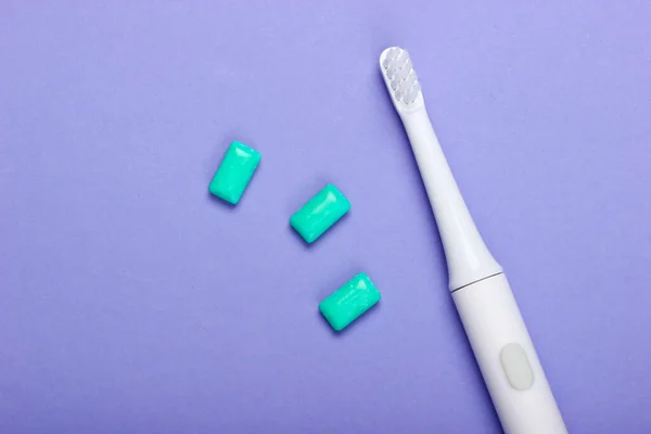 Elektrische Zahnbürste Mit Kaugummi Auf Violettem Hintergrund Pflege Der Zahngesundheit — Stockfoto