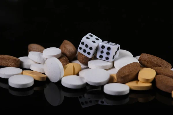 Dice and pills on black background. Game Addiction Treatment