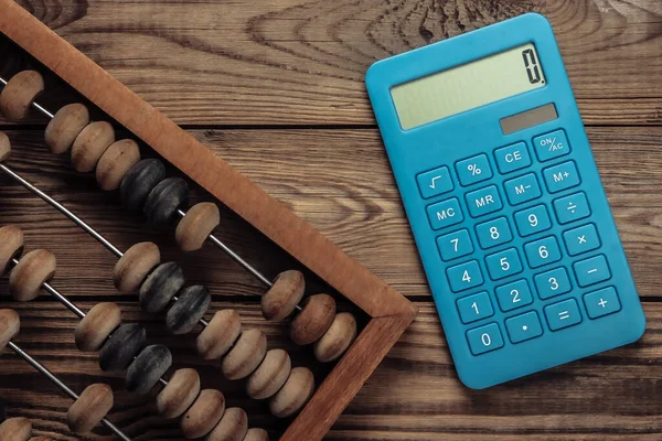 Vintage abacus and calculator on a wooden background. Top view.