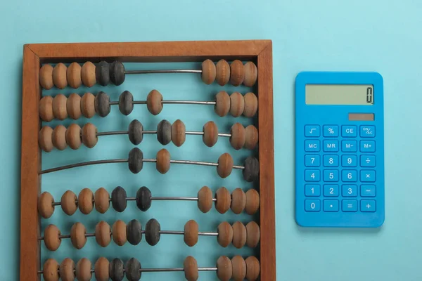 Vintage abacus and calculator on a blue pastel background. Top view.