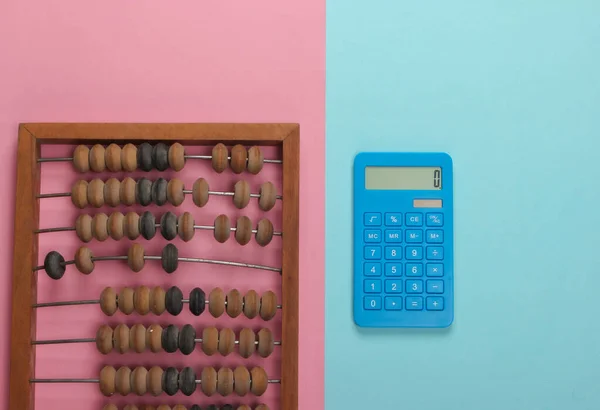 Vintage abacus and calculator on pink blue pastel   background. Top view.