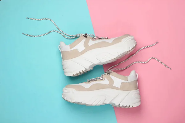 Pembe arka planda yüksek tabanlı (platform) şık spor ayakkabılar. Üst Manzara. Minimalizm