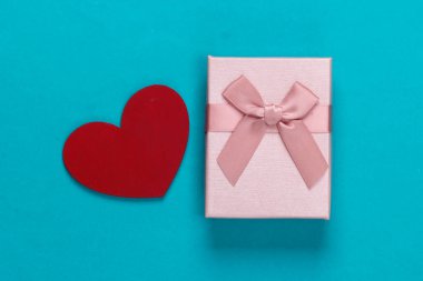 Mavi arka planda yay ve kalp olan hediye kutusu. Tatil, Sevgililer Günü. Üst Manzara. Minimalizm