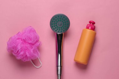 Duş alıyorum. Banyo süngerli duş başlığı, pembe pastel arka planda bir şişe duş jeli. Üst görünüm