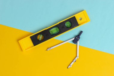 Sarı mavi stüdyo arka planında bina seviyesi ve pusula. Üst Manzara. Minimalizm