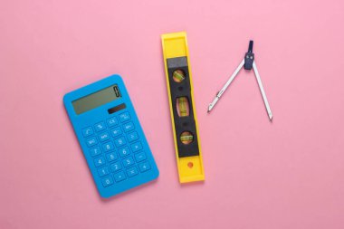 İnşaat seviyesi ve hesap makinesi, pembe stüdyo arka planında pusula. İnşaat aleti. Üst Manzara. Minimalizm