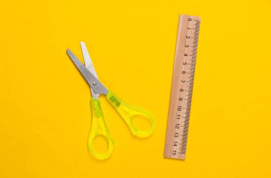 Kırtasiye (okul) makası, sarı arkaplanda cetvel. Okul malzemeleri. Üst Manzara. Minimalizm