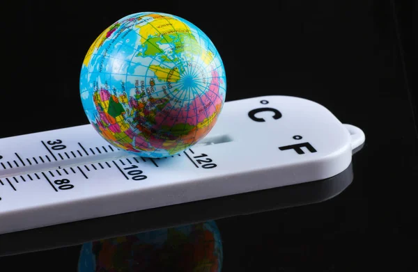 Climate control. Global warming. Weather thermometer with globe on black background.