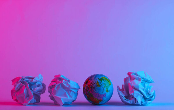 Глобус с мятыми бумажными шариками в модном неоновом свете. Серо-розово-голубой блеск. Концептуальное искусство. Минимализм