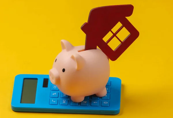 Save up for housing. Piggy bank with house figure, calculator on yellow background