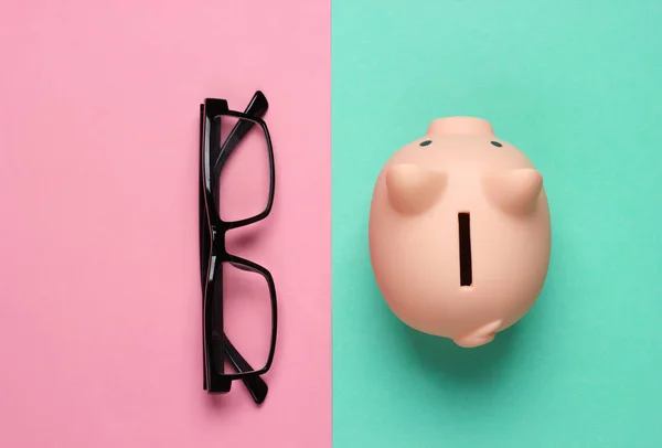 Piggy Bank Och Glasögon Rosa Blå Bakgrund Minimalistisk Studioshot Ovansidan — Stockfoto