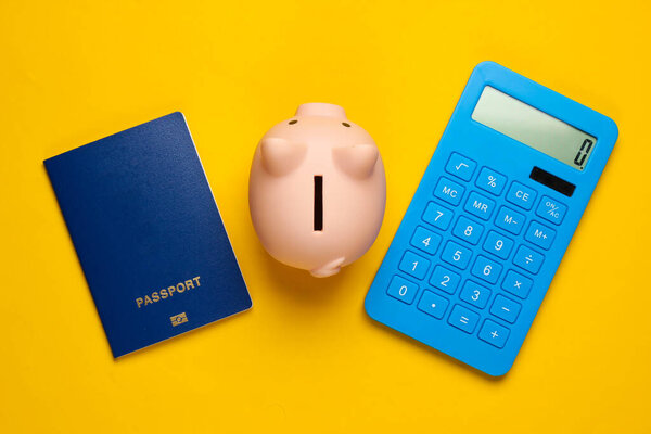 Save up for travel or emigration. Piggy bank with passport, calculator on yellow background. Top view. Flat lay