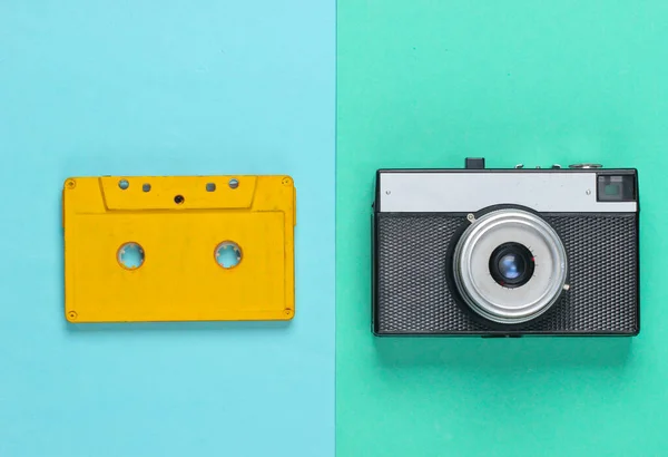 Retro audio cassette and film camera on blue background. 80s. Top view