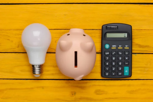 Poupar Electricidade Lâmpada Led Banco Porquinho Calculadora Fundo Madeira Amarelo — Fotografia de Stock