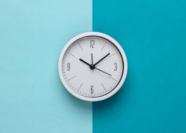 Mavi arka planda beyaz saat. Minimalist stüdyo çekimi. Üst görünüm