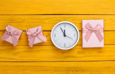 Noel, yeni yıl teması. Sarı ahşap arka planda saati olan hediye kutuları. Üst görünüm