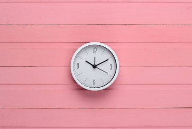 Pembe ahşap arka planda beyaz saat. Zaman geçiyor. Üst görünüm