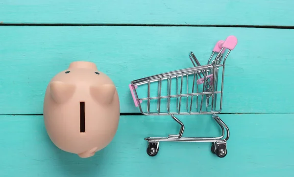 Winkelconcept Economie Piggy Bank Met Supermarkt Trolley Blauwe Houten Achtergrond — Stockfoto