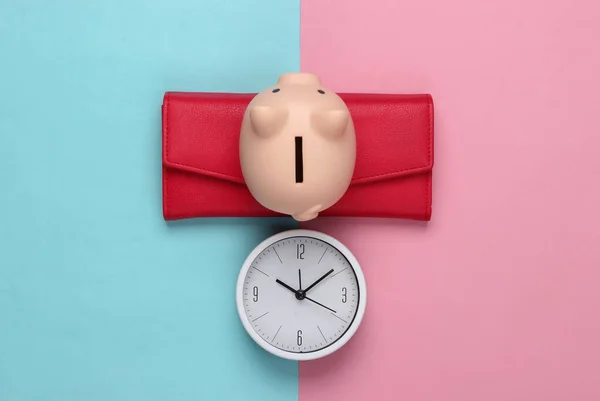 Time to invest. Deposit. White clock and piggy bank, wallet on pink blue pastel background. Minimalistic studio shot. Top view