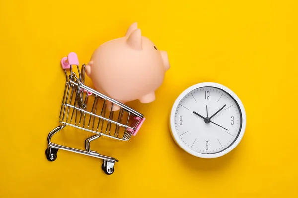 Čas Nakupovat Vozík Supermarketu Prasečí Bankou Hodiny Žlutém Pozadí Minimalismus — Stock fotografie