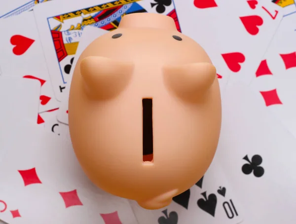 Piggy bank on playing cards. Top view. Game addiction