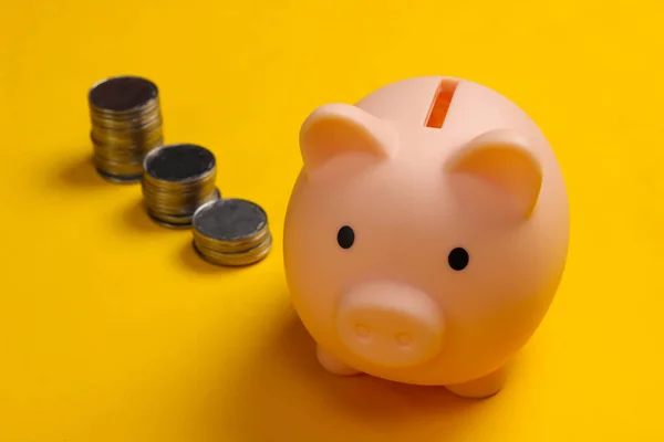 Piggy bank and stack of coins on yellow background, saving money, wealth and financial for investment