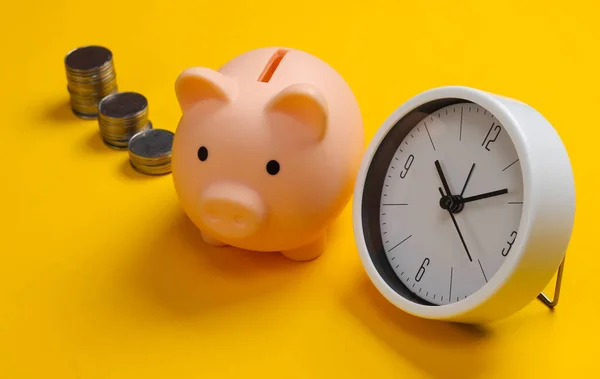 Piggy bank, clock and stack of coins on yellow background, saving money, wealth and financial for investment, deposit, time is money