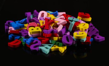 Birçok renkli ahşap harf siyah arkaplanda izole edilmiş..