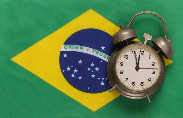 Vintage alarm clock on background of Brazil flag