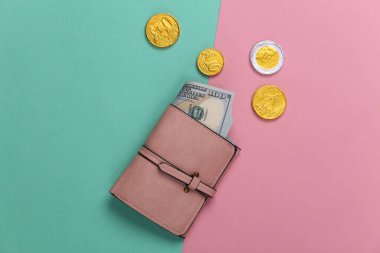 Deri cüzdan, yüz dolarlık banknotlar ve mavi-pembe pastel arka planda paralar. Üst görünüm