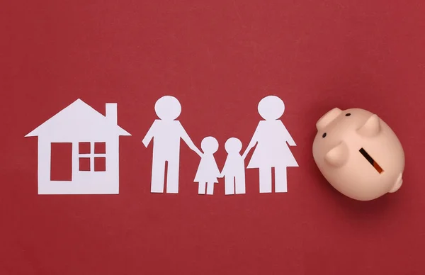 Paper happy family together with house and piggy bank on red background. Family budget