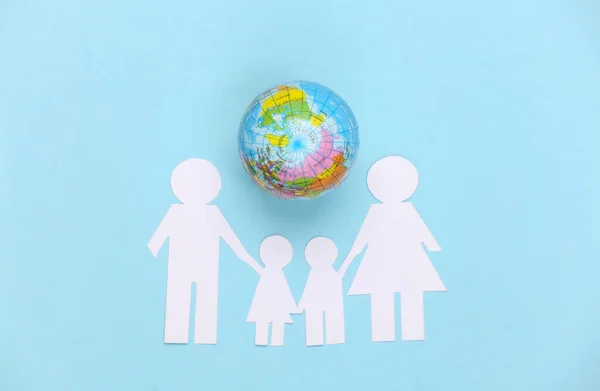 Paper family together with globe on blue background. Concept of ecology, population, family, earth day. World our house