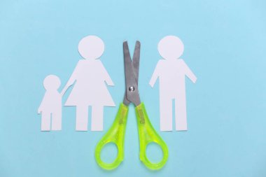 Dağılmış aile, boşanma. Mavi pastel arka planda makas kesimi kağıt ailesi