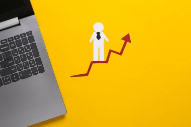 Dizüstü bilgisayar, kağıt işleriyle uğraşan bir adam. Sarı arka plan. Finansal ve sosyal başarının sembolü, ilerlemeye giden merdiven. Kariyer basamağı.