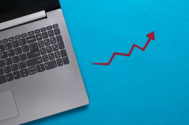 Çevrimiçi iş, ticaret. Mavi arka planda kırmızı ok olan dizüstü bilgisayar. Ok grafiği yükseliyor.