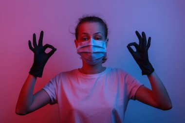 Her şey kontrol altında. Tıbbi maske ve eldiven takan rahat kadın iyi bir sembol olduğunu gösteriyor. Kırmızı-mavi eğimli neon ışığı