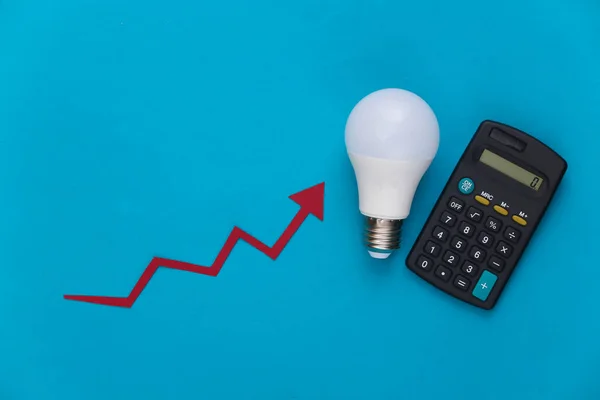 The concept of calculating energy consumption, modernization. Growth arrow tending up with light bulb and calculator on blue background