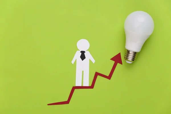 The concept of career and social growth. Paper man on a rising arrow with a light bulb. Green background.