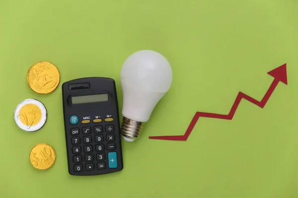 The concept of calculating energy consumption, modernization. Growth arrow tending up with light bulb, coins and calculator on green background