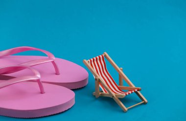 Flip flops ve mavi arka planda mini plaj sandalyesi. Plaj tatili, tatil köyü sembolü. Rahatla, yaz asgari konsepti