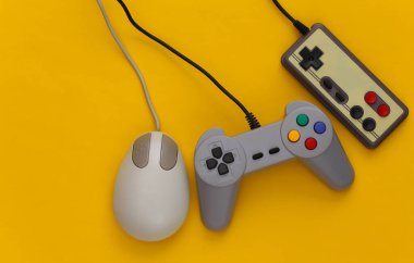 Sarı arka planda retro joystickler ve bilgisayar faresi. Retro oyun, oyun aletleri, aygıtlar