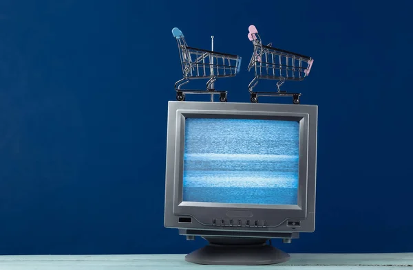 TV shop. Antenna old-fashioned retro tv with mini supermarket trolley on classic blue background