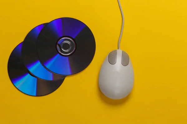 Old-fashioned retro CD\'s and pc mouse on yellow background. Top view
