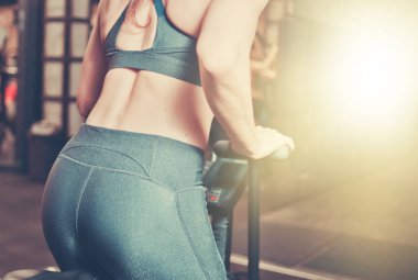 Spor kıyafetli kadın jimnastik salonunda bisiklet egzersizi yapıyor.