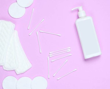 Pembe pastel arka planda hijyen ürünleri. Pamuk pedler, kadın pedleri, bir şişe krem, pamuk çubuklar. Üst görünüm, düz görünüm, Spac kopyala